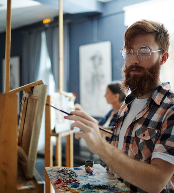 Skilled guy with palette painting something on easel